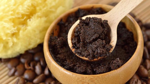 Homemade coffee scrub face mask in wooden bowl with spoon on coffee beans