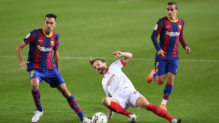 BARCELONA, SPAIN - OCTOBER 04: Sergio Busquets of Barcelona and Antoine Griezmann of Barcelona  battles for possession with  Ivan Rakitic of Sevilla FC  during the La Liga Santander match between FC Barcelona and Sevilla FC at Camp Nou on October 04, 2020 in Barcelona, Spain. Football Stadiums around Europe remain empty due to the Coronavirus Pandemic as Government social distancing laws prohibit fans inside venues resulting in fixtures being played behind closed doors. (Photo by David Ramos/Getty Images)