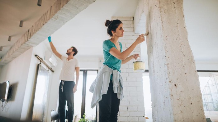 Ilustrasi renovasi rumah Young couple painting their living room