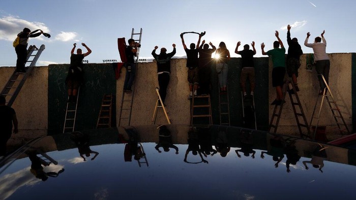 Warga Ceko Rela Naik Tangga Buat Nonton Apa? A fan carries his ladder to watch, from behind a fence, a Czech first division match between Bohemians Prague and Zlin in Prague, Czech Republic, Sunday, Oct. 4, 2020. Amid restrictive measures that limit the number of soccer fans from attending the game, fans are looking for innovative ways to watch the match during the ongoing coronavirus pandemic. (AP Photo/Petr David Josek)