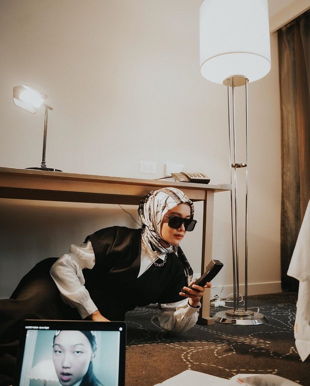 Terlihat Ana berpose di bawah kolong meja sambil memegang gagang telefon.