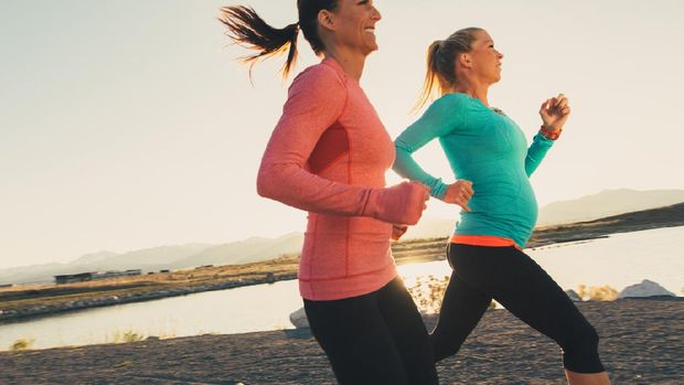 Two female runners in pink and blue athletic shirts are training for their next race. These women enjoy running at sunset in the evening together as friends on the trails through. Running is their way of staying active and healthy.