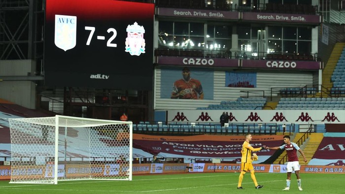 BIRMINGHAM, ENGLAND - OCTOBER 04: Adrian of Liverpool  shakes hands with Ollie Watkins of Aston Villa as the final score of 7-2 is seen on the big screen behind during the Premier League match between Aston Villa and Liverpool at Villa Park on October 04, 2020 in Birmingham, England. Sporting stadiums around the UK remain under strict restrictions due to the Coronavirus Pandemic as Government social distancing laws prohibit fans inside venues resulting in games being played behind closed doors. (Photo by Peter Powell - Pool/Getty Images)