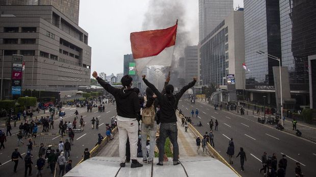 Massa aksi mengibarkan bendera saat unjuk rasa menolak pengesahan Undang-Undang Cipta Kerja di kawasan Jalan M.H. Thamrin, Jakarta, Kamis (8/10/2020). Unjuk rasa tersebut berakhir ricuh dan mengakibatkan sejumlah fasilitas umum rusak. ANTARA FOTO/Dhemas Reviyanto/aww.