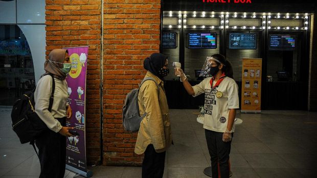 Petugas memeriksa suhu tubuh pengunjung yang akan menonton film di salah satu bioskop di Kota Bandung, Jawa Barat, Jumat (9/10/2020). Pemerintah Kota Bandung kembali mengizinkan bioskop kembali beroperasi dengan menerapkan protokol kesehatan COVID-19. ANTARA FOTO/Raisan Al Farisi/pras.