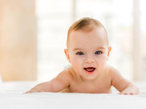 Portrait of happy baby boy lying down in bed and looking at camera.