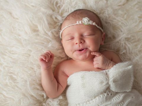 bayi perempuan A seven day old newborn baby girl with a cute expression. She is sleeping in a cream colored flokati.