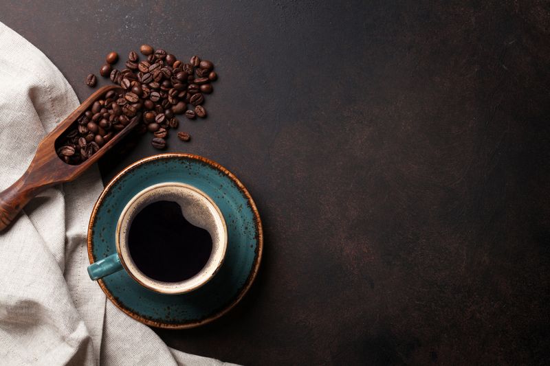 Coffee cup and beans on old kitchen table. Top view with copyspace for your text