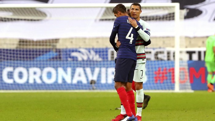 FILE - In this Sunday, Oct. 11, 2020 file photo Portugals Cristiano Ronaldo and Frances Raphael Varane greet each other at the end of the UEFA Nations League soccer match between France and Portugal at the Stade de France in Saint-Denis, north of Paris, France. The Portuguese soccer federation says Cristiano Ronaldo has tested positive for the coronavirus. The federation says Ronaldo is doing well and has no symptoms. He has been dropped from the countrys Nations League match against Sweden on Wednesday, Oct. 14. (AP Photo/Thibault Camus, File)
