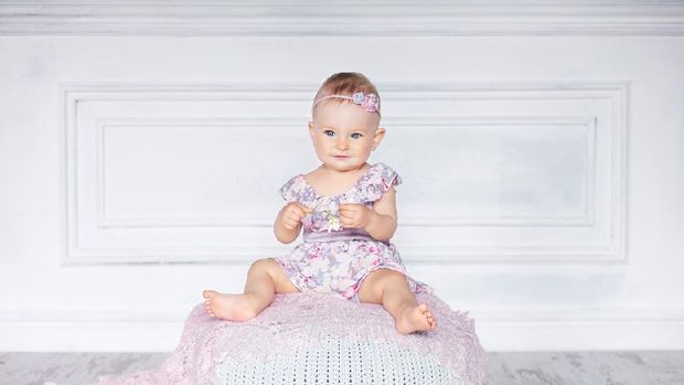 Little pretty girl with blue eyes sits on a padded stool