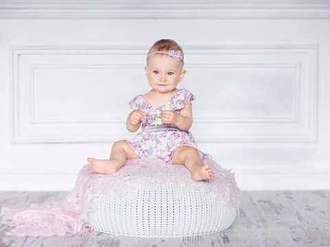 Little pretty girl with blue eyes sits on a padded stool