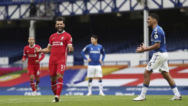 Liverpool's Mohamed Salah, 11, celebrates scoring his side's second goal as Everton's Allan, 6, reacts during the English Premier League soccer match between Everton and Liverpool at Goodison Park stadium, in Liverpool, England, Saturday, Oct. 17, 2020. (Cath Ivill/Pool via AP)