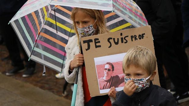A child holds up a a poster of Samuel Paty as people gather on Republique square in Lille, northern France, Sunday Oct. 18, 2020. Demonstrators in France on Sunday took part in gatherings in support of freedom of speech and in tribute to a history teacher who was beheaded near Paris after discussing caricatures of Islam’s Prophet Muhammad with his class. (AP Photo/Michel Spingler)
