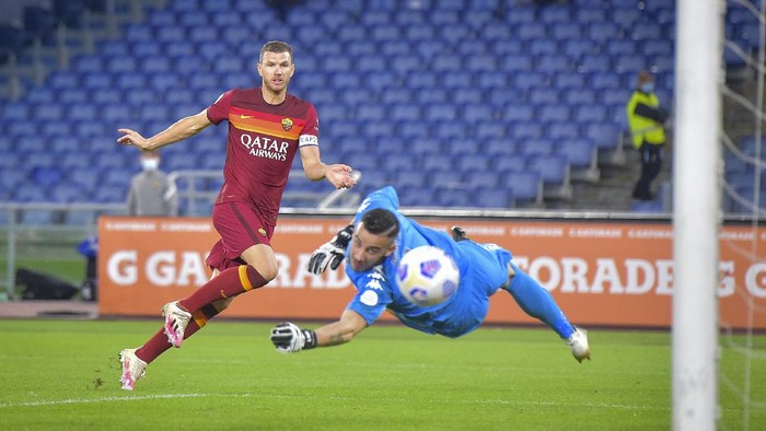 Romas Edin Dzeko puts the ball past Benevento goalkeeper Lorenzo Montipo during the Italian Serie A soccer match between AS Roma and Benevento, at the Olympic stadium in Roma, Sunday, Oct. 18, 2020. (Fabio Rossi/LaPresse via AP)