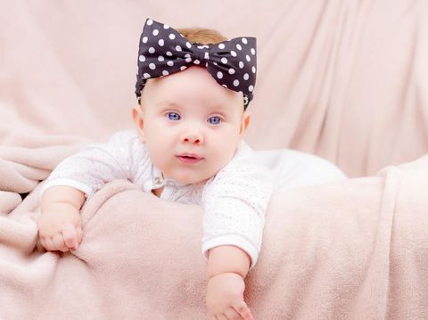 Portrait of a beautiful baby girl with the black band on her head  lying on the sofa
