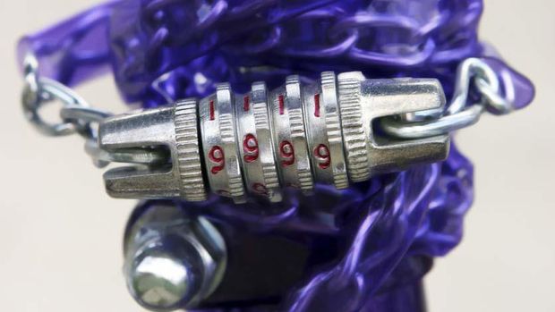 Closeup of a purple bicycle combination chain lock wrapped around the seat post of a purple bike.