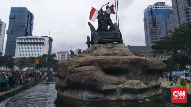 Massa aksi demo tolak omnibus law naik ke atas patung arjunawiwaha mengubarkan bendera merah putih. CNN Indonesia/ Rizki Ramadhan