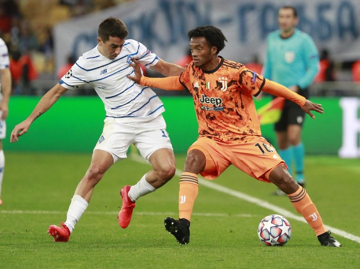 =Juventus Juan Cuadrado challenges for the ball with Dynamo Kyivs Artem Shabanov during the Champions League, group G, soccer match between Dynamo Kyiv and Juventus at the Olimpiyskiy Stadium in Kyiv, Ukraine, Tuesday, Oct. 20, 2020. (Valentyn Ogirenko/Pool via AP)