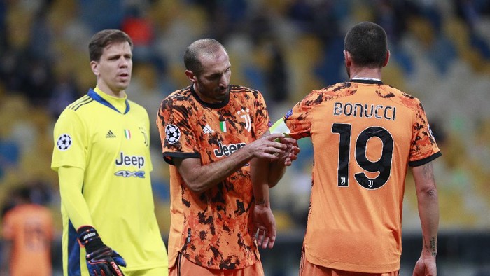 Juventus Giorgio Chiellini, center, adjusts the captains hand band on Juventus Leonardo Bonucci during the Champions League, group G, soccer match between Dynamo Kyiv and Juventus at the Olimpiyskiy Stadium in Kyiv, Ukraine, Tuesday, Oct. 20, 2020. (Valentyn Ogirenko/Pool via AP)