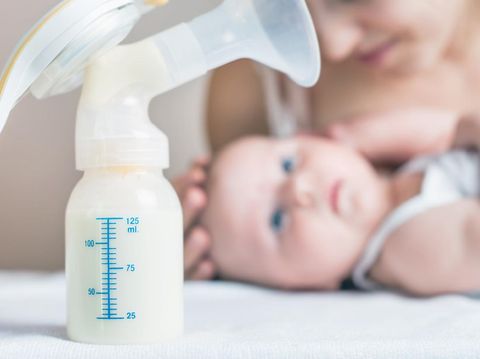 Manual breast pump, mothers breast milk is the most healthy food for newborn baby. Happy mother with baby at background