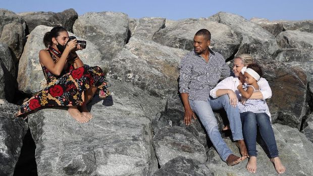 Freelance lifestyle photographer, Paula Hainey takes photos of Darrin Chapman, a pilot recently laid off by long-haul carrier Emirates, and his wife, Jodi Chapman, who carries their daughter Harper, in Dubai, United Arab Emirates, Wednesday, Oct. 14, 2020. Hainey is providing free photoshoots to laid-off expats forced to leave the skyscraper-studded Persian Gulf city because of the coronavirus pandemic. (AP Photo/Kamran Jebreili)