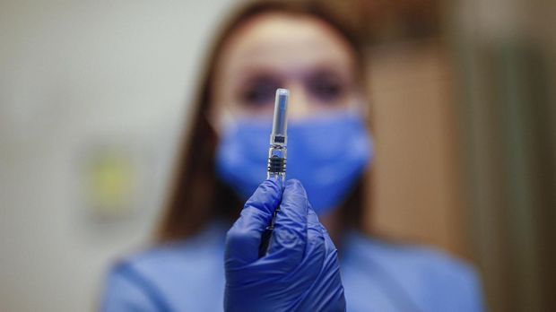 A health worker displays a dose of a COVID-19 vaccine currently on phase III clinical trials to be administered to Cem Gun, an Emergency Medicine Physician at the Acibadem Hospital in Istanbul, Friday, Oct. 9, 2020. The vaccine developed in China by Sinovac Biotech, was approved for trials by Health Institutes of Turkey (TUSEB) in 26 private hospitals in the country. (AP Photo/Emrah Gurel)