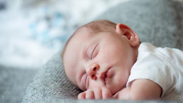 Cute little newborn baby boy lying on bed, sleeping, close up