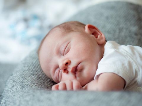 Cute little newborn baby boy lying on bed, sleeping, close up