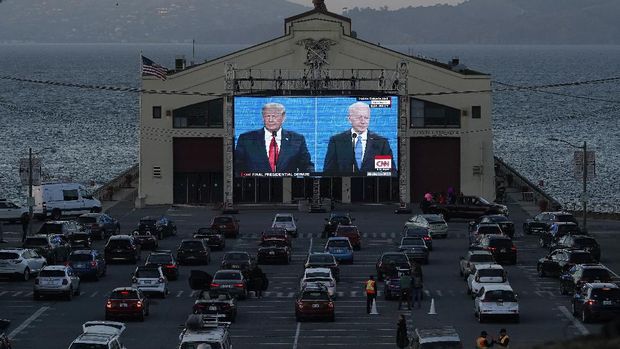 People watch from their vehicles as President Donald Trump, on left of video screen, and Democratic presidential candidate former Vice President Joe Biden speak during a Presidential Debate Watch Party at Fort Mason Center in San Francisco, Thursday, Oct. 22, 2020. The debate party was organized by Manny's, a San Francisco community meeting and learning place. (AP Photo/Jeff Chiu)