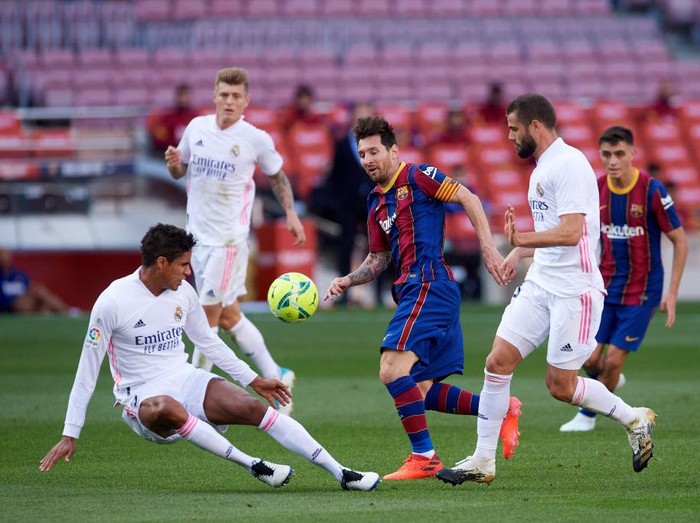 BARCELONA, SPAIN - OCTOBER 24: Lionel Messi of FC Barcelona runs with the ball amongst Raphael Varane and Nacho Fernandez of Real Madrid CF during the La Liga Santander match between FC Barcelona and Real Madrid at Camp Nou on October 24, 2020 in Barcelona, Spain. Sporting stadiums around Spain remain under strict restrictions due to the Coronavirus Pandemic as Government social distancing laws prohibit fans inside venues resulting in games being played behind closed doors. (Photo by Alex Caparros/Getty Images)