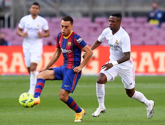 BARCELONA, SPAIN - OCTOBER 24: Sergino Dest of Barcelona  battles for possession with  Vinicius Junior of Real Madrid  during the La Liga Santander match between FC Barcelona and Real Madrid at Camp Nou on October 24, 2020 in Barcelona, Spain. Sporting stadiums around Spain remain under strict restrictions due to the Coronavirus Pandemic as Government social distancing laws prohibit fans inside venues resulting in games being played behind closed doors. (Photo by Alex Caparros/Getty Images)