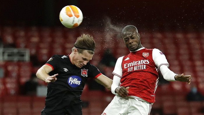 Arsenals Nicolas Pepe, right, and Dundalks Daniel Cleary compete to head the ball during the Europa League Group B soccer match between Arsenal and Dundalk at the Emirates Stadium in London, Thursday, Oct. 29. 2020. (AP Photo/Matt Dunham)