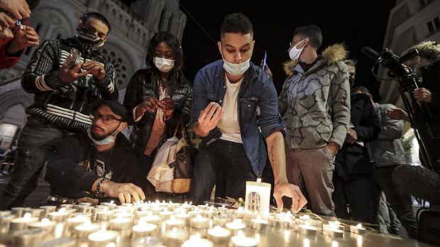 People lights candle outside the Notre-Dame de l'Assomption Basilica in Nice on October 29, 2020 in tribute to the three victims of a knife attacker, cutting the throat of at least one woman, inside the church of the French Riviera city. (Photo by Valery HACHE / AFP)