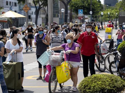 Lima, Peru - April 4 2020: Woman with bike and groceries wearing mask amid coronavirus outbreak in South America. Only woman day, gender-based quarantine, women lined up to buy groceries.