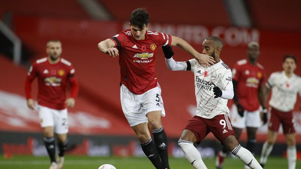 Manchester United's Harry Maguire, left, is challenged by Arsenal's Alexandre Lacazette during the English Premier League soccer match between Manchester United and Arsenal at the Old Trafford stadium in Manchester, England, Sunday, Nov. 1, 2020. (Phil Noble/Pool via AP)