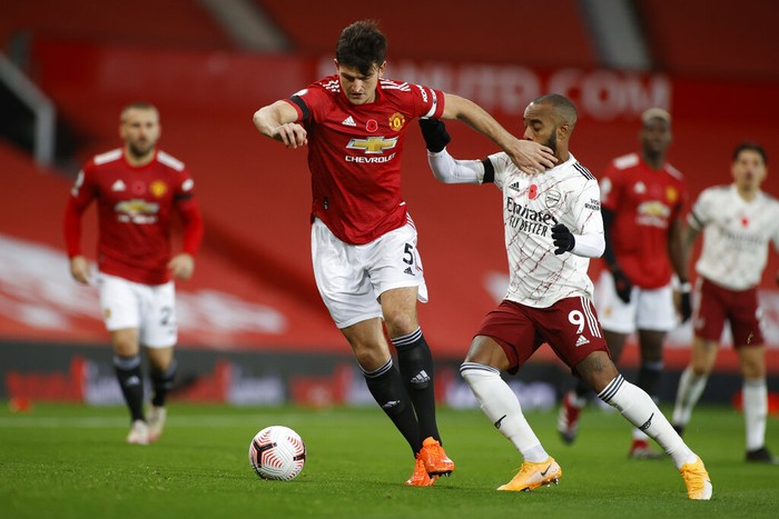 Manchester Uniteds Harry Maguire, left, is challenged by Arsenals Alexandre Lacazette during the English Premier League soccer match between Manchester United and Arsenal at the Old Trafford stadium in Manchester, England, Sunday, Nov. 1, 2020. (Phil Noble/Pool via AP)