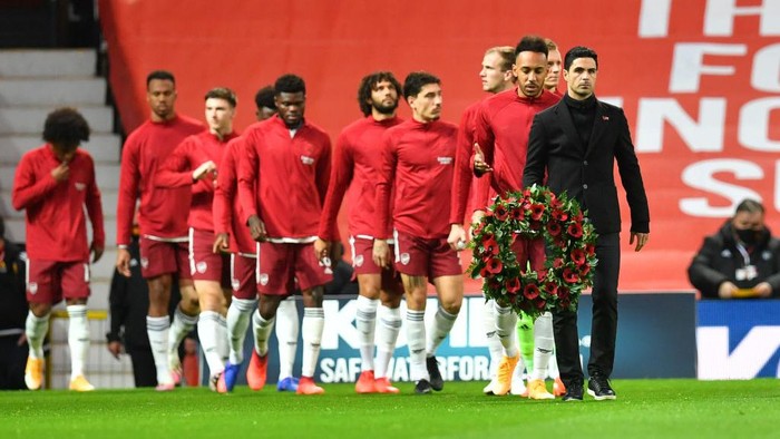MANCHESTER, ENGLAND - NOVEMBER 01: Mikel Arteta, Manager of Arsenal leads his team out whilst carrying a Poppy Wreath to the centre circle in order to mark Remembrance Day prior to the Premier League match between Manchester United and Arsenal at Old Trafford on November 01, 2020 in Manchester, England. Sporting stadiums around the UK remain under strict restrictions due to the Coronavirus Pandemic as Government social distancing laws prohibit fans inside venues resulting in games being played behind closed doors. (Photo by Paul Ellis - Pool/Getty Images)