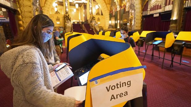 First time voter Sarah Facterman votes on a Ballot Marking Device (BMD) inside the Hollywood Pantages Theatre in Los Angeles, Saturday, Oct. 31, 2020. In-person voting has started in most counties across California. To curb spread of the coronavirus the Legislature allowed counties to offer fewer in-person polling places in exchange for opening them earlier. Voting locations opened Friday in some places and most counties will have it this weekend through Election Day on Tuesday.  (AP Photo/Damian Dovarganes)
