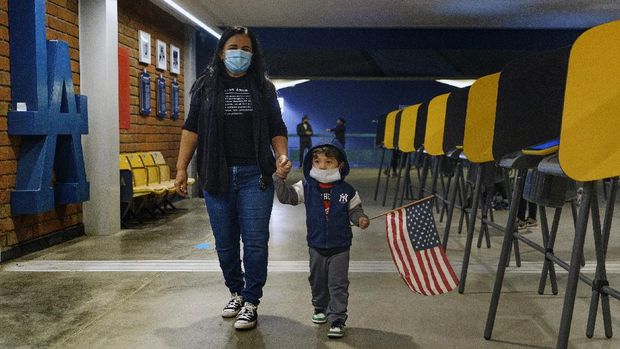 Lisa Carrera, a former Los Angeles Unified School history teacher from La Puente, Calif., holds the hand of her grandson Maverick, 2, after casting her ballot in-person at the Top of the Park at Dodger Stadium in Los Angeles, Monday, Nov. 2, 2020. Turnout has been massive during the early voting period as Californians cast ballots for president, the state Legislature, local offices and on a dozen statewide propositions. By Monday more than 11 million people had already returned their ballots. (AP Photo/Damian Dovarganes)
