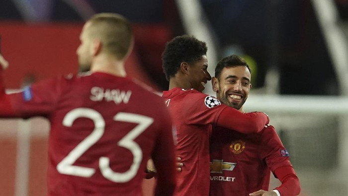 Manchester Uniteds Marcus Rashford, center, celebrates with Manchester Uniteds Bruno Fernandes after scoring his sides second goal during the Champions League group H soccer match between Manchester United and RB Leipzig, at the Old Trafford stadium in Manchester, England, Wednesday, Oct. 28, 2020. (AP Photo/Dave Thompson)