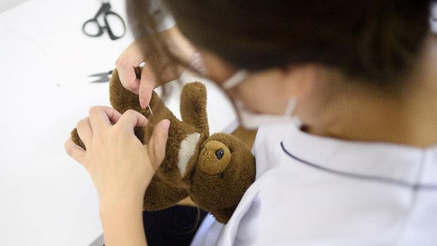 This picture taken on September 13, 2020 shows founder Natsumi Hakozaki doing a quick repair for a stuffed toy bear at Natsumi Clinic in Tokyo. - The clinic specialises in restoring much-loved teddies and other cuddly toys to their original glory, delighting deeply attached owners. (Photo by Philip FONG / AFP) / TO GO WITH STORY Japan-lifestyle-toys