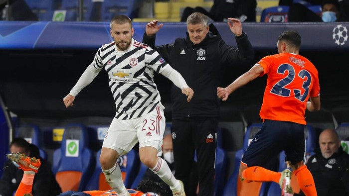 Manchester Uniteds manager Ole Gunnar Solskjaer, background, gestures as Manchester Uniteds Luke Shaw, left, fights for the ball with Basaksehirs Aziz Behich during the Champions League group H soccer match between Istanbul Basaksehir and Manchester United at the Fatih Terim stadium in Istanbul, Wednesday, Nov. 4, 2020. (AP Photo)
