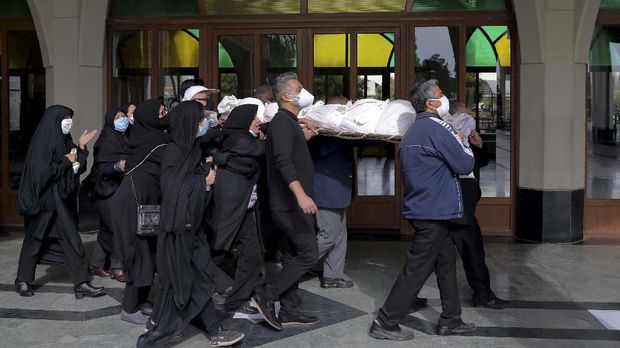 Mourners carry the body of a person who died from COVID-19, at the Behesht-e-Zahra cemetery on the outskirts of the Iranian capital, Tehran, Iran, Sunday, Nov. 1, 2020. The cemetery is struggling to keep up with the coronavirus pandemic ravaging Iran, with double the usual number of bodies arriving each day and grave diggers excavating thousands of new plots. (AP Photo/Ebrahim Noroozi)