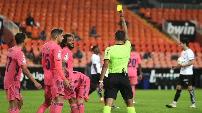 VALENCIA, SPAIN - NOVEMBER 08: Marcelo of Real Madrid is shown a yellow card by referee Jesus Gil Manzano awards a penalty to Valencia during the La Liga Santander match between Valencia CF and Real Madrid at Estadio Mestalla on November 08, 2020 in Valencia, Spain. Sporting stadiums around Spain remain under strict restrictions due to the Coronavirus Pandemic as Government social distancing laws prohibit fans inside venues resulting in games being played behind closed doors. (Photo by Angel Martinez/Getty Images)