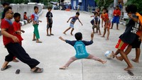 Sejumlah anak-anak tengah bermain sepakbola di Jalan Inspeksi Ciliwung di kawasan Bukit Duri, Jakarta.