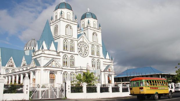 Exterior of Immaculate Conception of Mary Cathedral, Apia, and a local bus passing in front of it. Located in the center of the capital city, Apia, you will find this beautiful church with stained glass and art on the walls.