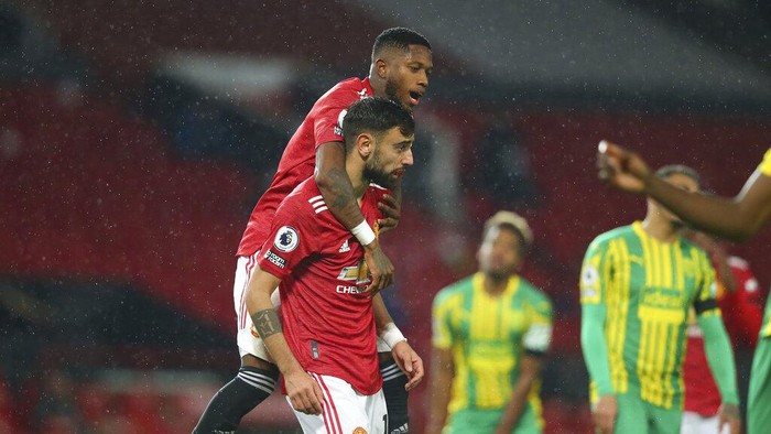 Manchester Uniteds Fred, top, celebrates after Manchester Uniteds Bruno Fernandes, center, scored the opening goal from the penalty spot during the English Premier League soccer match between Manchester United and West Bromwich Albion at the Old Trafford stadium in Manchester, England, Saturday, Nov. 21, 2020. (Alex Livesey/Pool via AP)