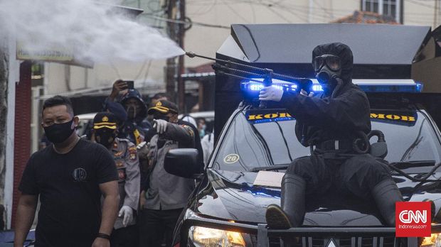 Anggota kepolisian Polda Metro Jaya menggunakan Alat Pelindung Diri (APD) saat melakukan penyemprotan di kawasan Petamburan, Jakarta, Minggu, 22 November 2020. Penyemprotan tersebut dilakukan sebagai upaya pencegahan penyebaran Covid-19. CNN Indonesia/Bisma Septalisma