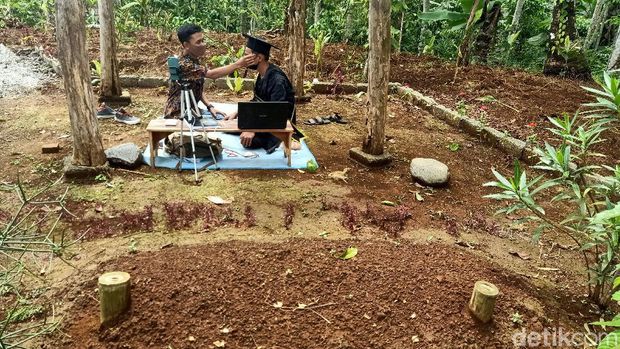 Mochamad Nadif Nasrulloh (23) mengikuti wisuda virtual di depan makam bapaknya, Desa Sidarata, Banjarnegara, Selasa (24/11/2020)