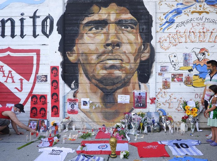 Diego Maradona BUENOS AIRES, ARGENTINA - NOVEMBER 25: A fan mourning Diego Maradona places a picture in an altar outside Argentinos Juniors' Diego Maradona Stadium on November 25, 2020 in Buenos Aires, Argentina. Diego Maradona, considered one of the biggest football stars in history, died at 60 from a heart attack on Wednesday in Buenos Aires. (Photo by Fernando de Dios/Getty Images)